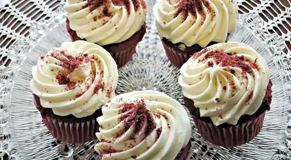 Fem röda sammetsmuffins med fluffig cream cheese frosting, strösslade med smulor.