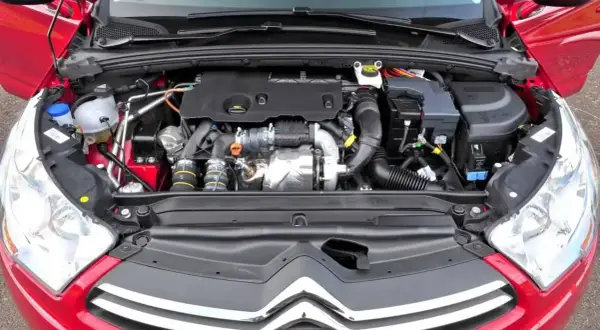 Silnik w czerwonym Citroen C4 2008. Widok komory silnika z turbosprężarką i przewodami.