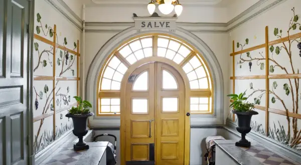 Entréhall med jugendstil hus-känsla. Dubbeldörrar med välvt fönster ovanför. Väggdekorationer med vinrankor.