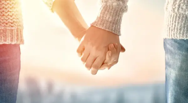 Manos entrelazadas bajo un sol cálido, un símbolo de una profunda **relación kármica** que trasciende el tiempo.