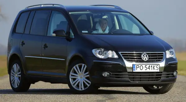 Czarny Volkswagen Touran 2004 z kierowcą w kapturze, widok z przodu.