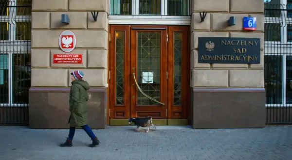 Przed budynkiem Naczelnego Sądu Administracyjnego przechadza się kobieta z psem.