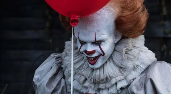 Przerażający klaun Pennywise, znany ze slasherów, trzyma czerwony balon.