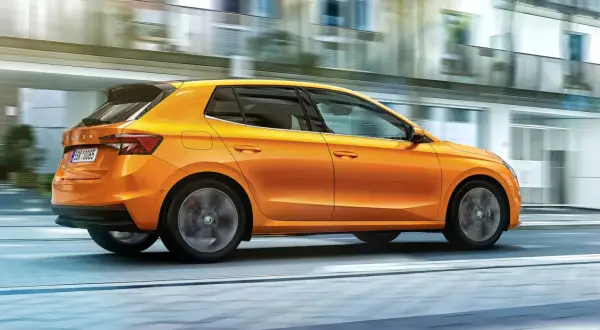 En orange Skoda Fabia kör snabbt genom staden. Inga problem med denna bil, bara ren körglädje.
