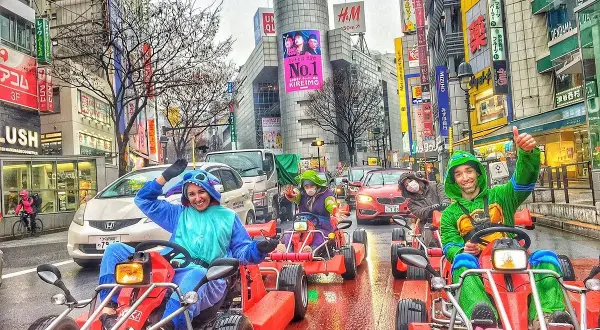 Folk i dräkter kör gokart genom Shibuya Crossing i Tokyo.