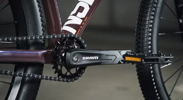 Zbliżenie na rowerowy mechanizm korbowy SRAM i łańcuch. Tabela przełożeń rowerowych jest kluczowa dla optymalnego pedałowania.