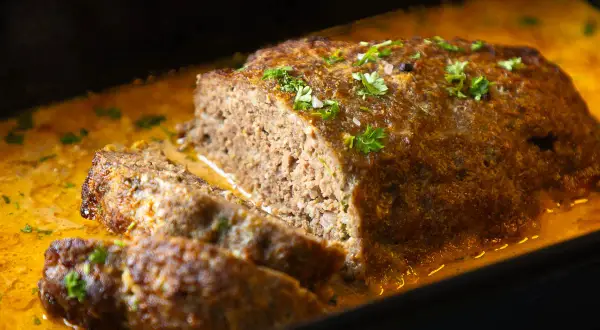 Saftiger Hackbraten mit cremiger Soße, garniert mit Petersilie. Ein köstliches Hackbraten Rezept für die ganze Familie.