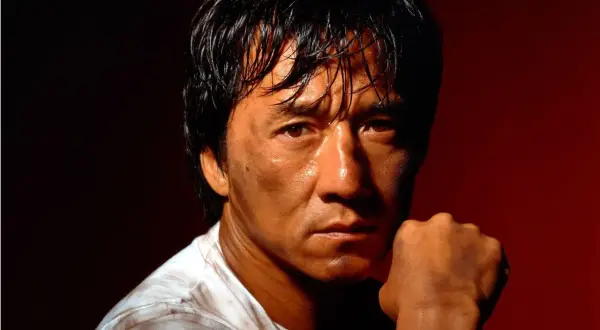 Jackie Chan, med svettig panna och en knuten näve, redo för action i sina filmer.