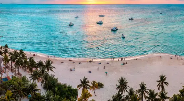 Piękna plaża z palmami i łodziami na turkusowym morzu. Idealne miejsce, by zastanowić się, kiedy lecieć do Cancun.
