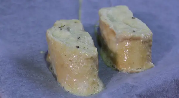 Dos trozos de pan empapados en huevo y leche, listos para hornearse como torrijas.