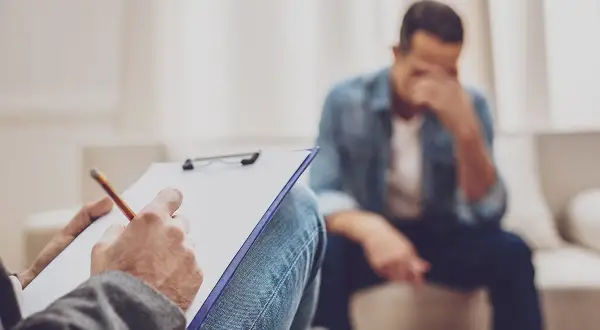 Terapeuta notuje podczas rozmowy z mężczyzną w depresji.