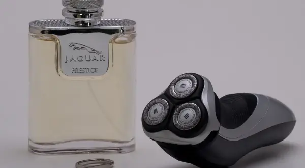 Flakon wody toaletowej Jaguar Prestige obok golarki elektrycznej i małych nożyczek.