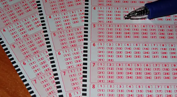 Kupony lotto i pytanie: czy wygrana w Jaka to melodia jest opodatkowana tak samo jak w lotto? Długopis nad polami do zaznaczenia liczb.