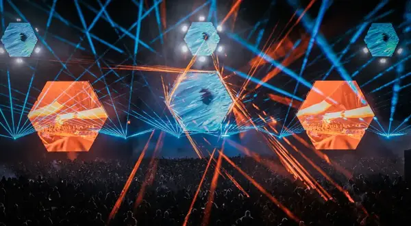 Koncertowa noc na festiwalu **Audioriver**. Tłum bawi się w rytm muzyki, a nad głowami wirują laserowe wiązki i sześciokątne ekrany z wizualizacjami.