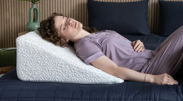 Woman sleeping on a wedge pillow. Learn how to make memory foam pillow expand faster for ultimate comfort.