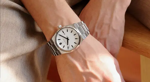 Elegancki zegarek na metalowej bransolecie na męskim nadgarstku. Klasyczny design, na której ręce nosi się zegarek, podkreśla styl.