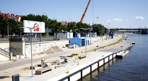 Trwa rewitalizacja Bulwaru Piastowskiego w Szczecinie. Widoczny plac budowy, dźwig i pracownicy nad Odrą.