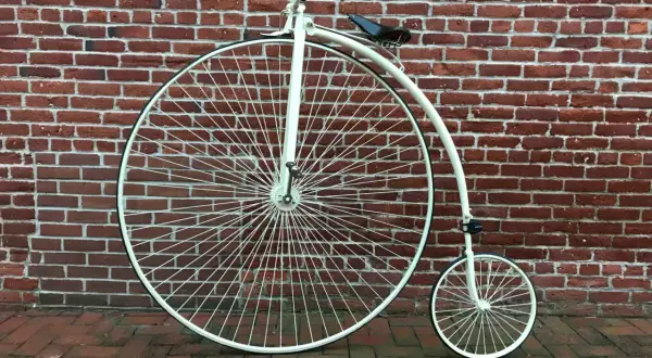 Ein Hochrad, ein Meilenstein in der Entwicklung Fahrrad, steht vor einer roten Ziegelwand.