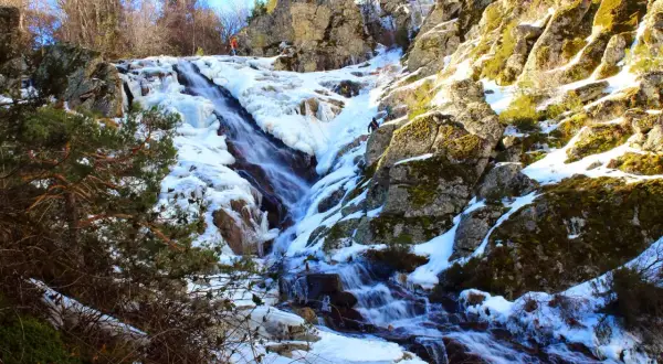 Cascada helada en el abedular de Canencia, con escaladores ascendiendo por el hielo y la roca.