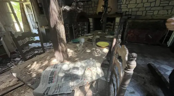 Table dressée dans une maison abandonnée, vestige d'un urbex à Bordeaux. Lumière filtrant par la fenêtre, poussière sur les assiettes.