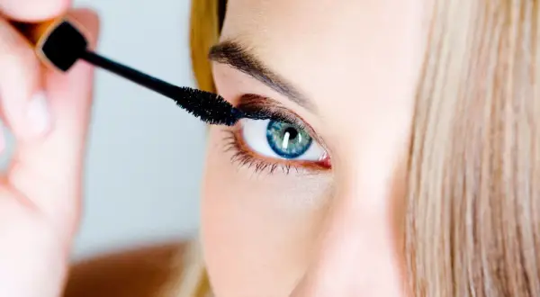Une femme applique du mascara. Pour savoir comment enlever du mascara waterproof, il faut un bon démaquillant.