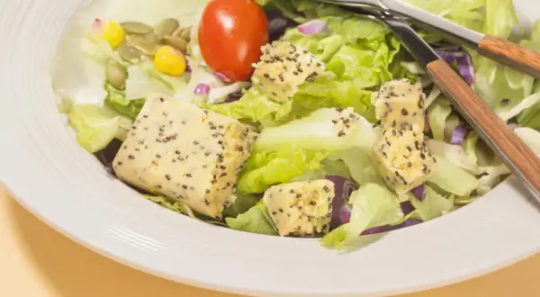 Salade fraîche avec cubes de tofu aux graines, maïs, tomate et graines de courge. Parfait pour savoir que manger après le sport.