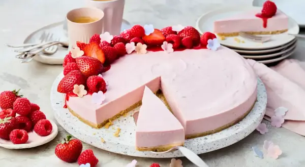 Ein köstlicher Erdbeer-Cheesecake ohne Backen, dekoriert mit frischen Beeren und kleinen Blüten. Perfekt für den Sommer!