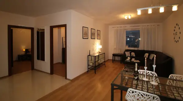 Nowoczesny sufit podwieszany w salonie, z eleganckim oświetleniem, tworzy przytulną atmosferę. Wnętrze jest stylowo urządzone.