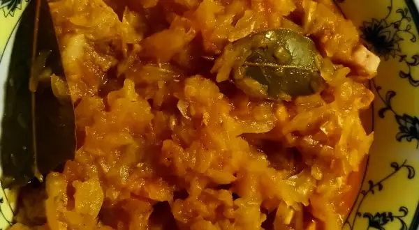Pyszny bigos ze słodkiej kapusty, z dodatkiem liści laurowych, w żółtej misce z ozdobnym wzorem.