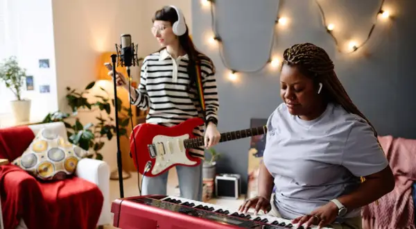 Dwie kobiety tworzą muzykę: jedna gra na keyboardzie, druga na gitarze. Słychać idealną harmonię instrumentów.
