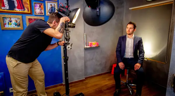 Fotograf robi zdjęcie mężczyźnie w garniturze w studiu fotograficznym.
