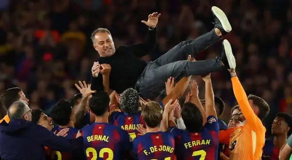Piłkarze FC Barcelona 22/23 unoszą trenera Xaviego w geście radości po wygranym meczu.