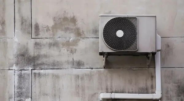 Unité extérieure d'une pompe à chaleur installée sur un mur en béton. Le système est prêt à fonctionner.