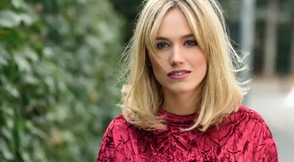 Blondynka w czerwonej, aksamitnej bluzce z modnym clavi cut.