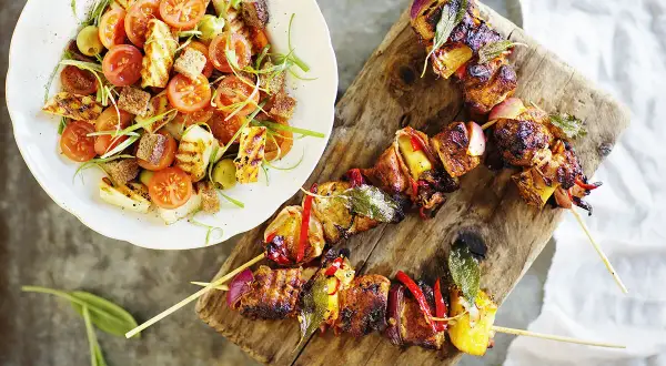 Grillspett med kött och grönsaker, serverade med en sallad på grillad halloumi, tomater och krutonger. Perfekt sommarmat recept för en härlig middag.