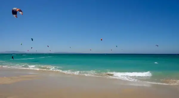 El levante en Tarifa impulsa a numerosos kitesurfistas sobre aguas turquesas. Un día perfecto para disfrutar del mar y el viento.