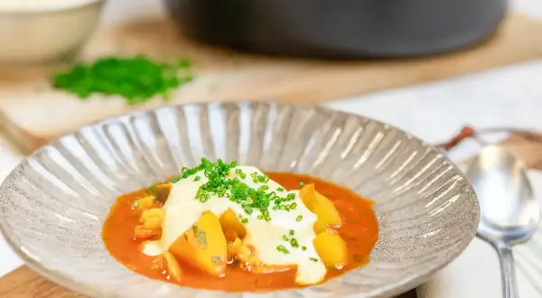 En vällagad fisksoppa med saffran, toppad med krutonger och färska örter. Serveras i en vacker skål med en sked bredvid.