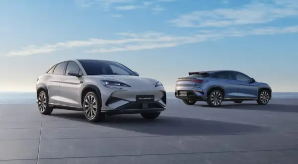 Dwa nowoczesne chińskie samochody elektryczne, BYD SEALION 7, stoją na tle błękitnego nieba i morza.