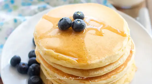 Pancakes soffici con albumi, guarniti con mirtilli freschi e sciroppo d'acero.