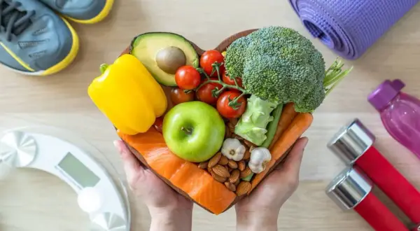 Un cuore di cibo sano: salmone, verdure, frutta, frutta secca e aglio. Capire cosa sono i carboidrati è fondamentale per una dieta equilibrata.