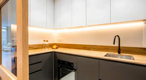 Cocinas negras y madera, con encimera de madera clara, armarios superiores blancos y detalles modernos.