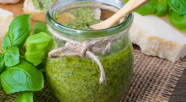 Frisches Pesto im Glas, zubereitet mit dem Thermomix, daneben Basilikum, Parmesan und Brot.