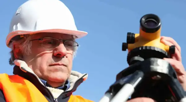 Geodeta w kasku i kamizelce odblaskowej pracuje z niwelatorem. Czy geodeta może wejść na posesję bez powiadomienia?
