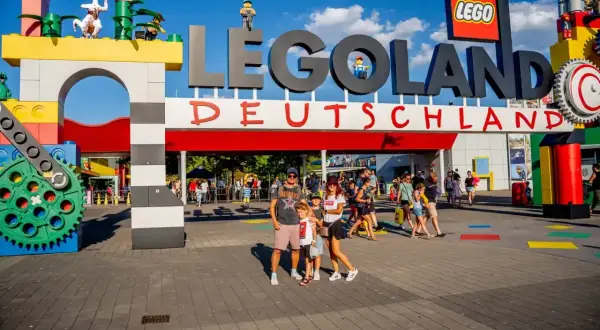Rodzina pozuje przed wejściem do Lego Land Deutschland. Kolorowe klocki i wielkie logo zapraszają do świata zabawy.
