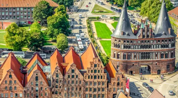 Blick auf Holstentor und historische Backsteinhäuser in Lübeck, ein Wahrzeichen vieler historischer Orte Deutschlands.