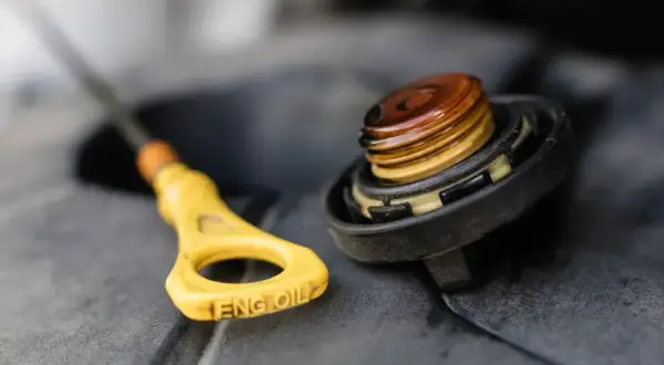 Żółta miarka z napisem "ENG OIL" i zakręcona nakrętka z widocznym olejem. Sprawdzanie, ile oleju do silnika, to podstawa.