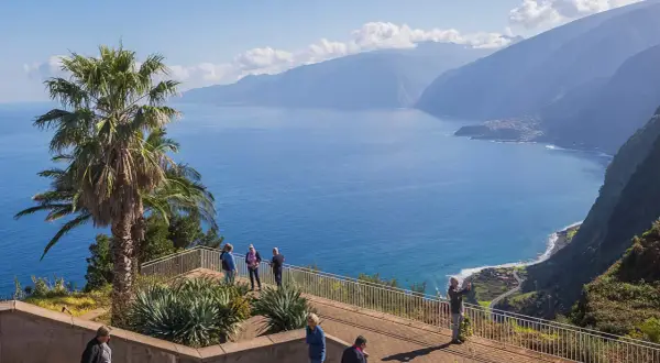 Blick auf Ribeira da Janela mit Palmen und dem tiefblauen Meer. Touristen genießen die Aussicht auf die Küste und die Berge.