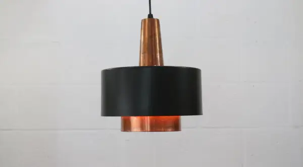 Stylowa lampa sufitowa z miedzi i czarnego metalu, dodająca ciepła wnętrzu.