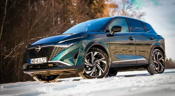 Zielony Nissan Qashqai Tekna na śniegu. Bogate wyposażenie tego SUV-a w zimowej scenerii.