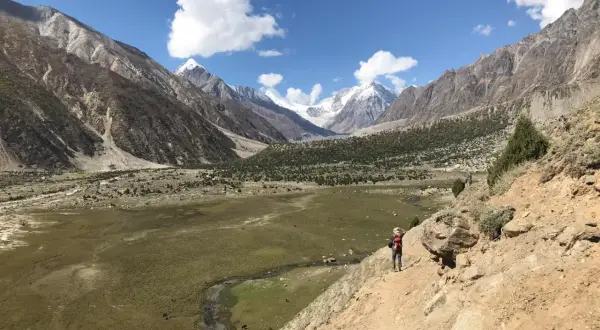 Wanderer auf einem Pfad im Rupal-Tal, umgeben von majestätischen Bergen und grünen Tälern.